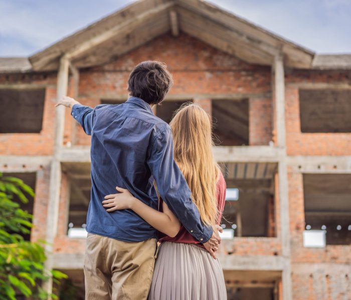 Para patrząca na swój nowy dom w budowie, planująca przyszłość i marząca. Młoda rodzina marząca o nowym domu. Koncepcja nieruchomości