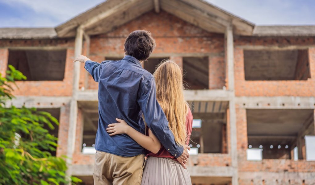 Para patrząca na swój nowy dom w budowie, planująca przyszłość i marząca. Młoda rodzina marząca o nowym domu. Koncepcja nieruchomości