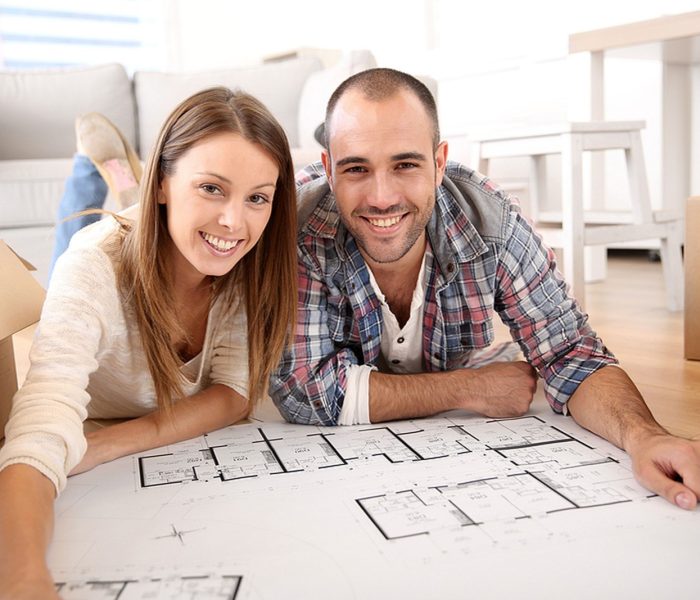 Wesoła para patrząca na plan budowy domu