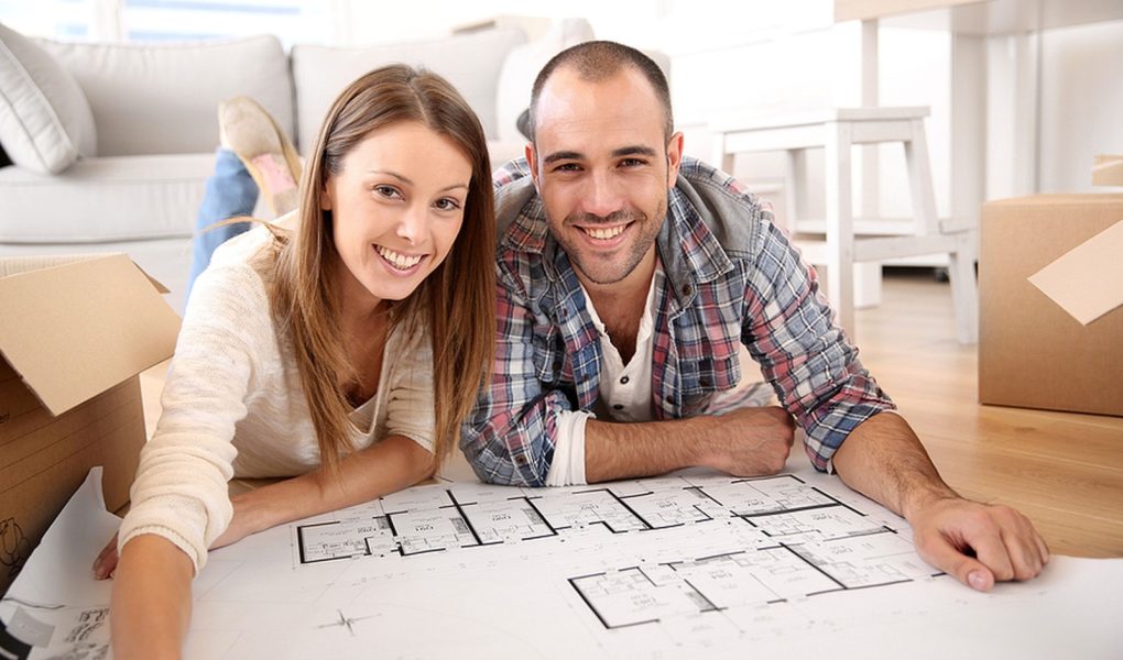 Wesoła para patrząca na plan budowy domu