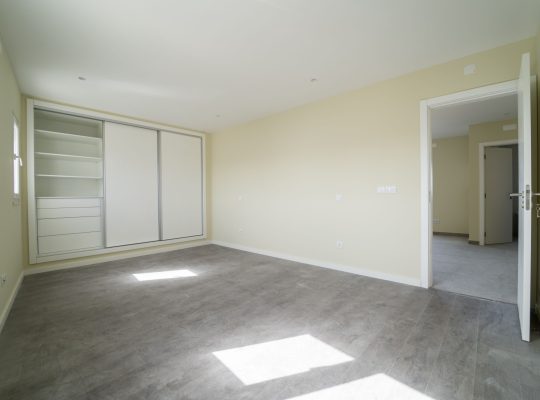 Pusty pokój z ciemną drewnianą podłogą laminowaną i szafą. Wnętrze domu, szeroka przestrzeń sypialni. Nowe, niedawno pomalowane mieszkanie lub dom. Drewniana podłoga. Zarządzanie nieruchomościami