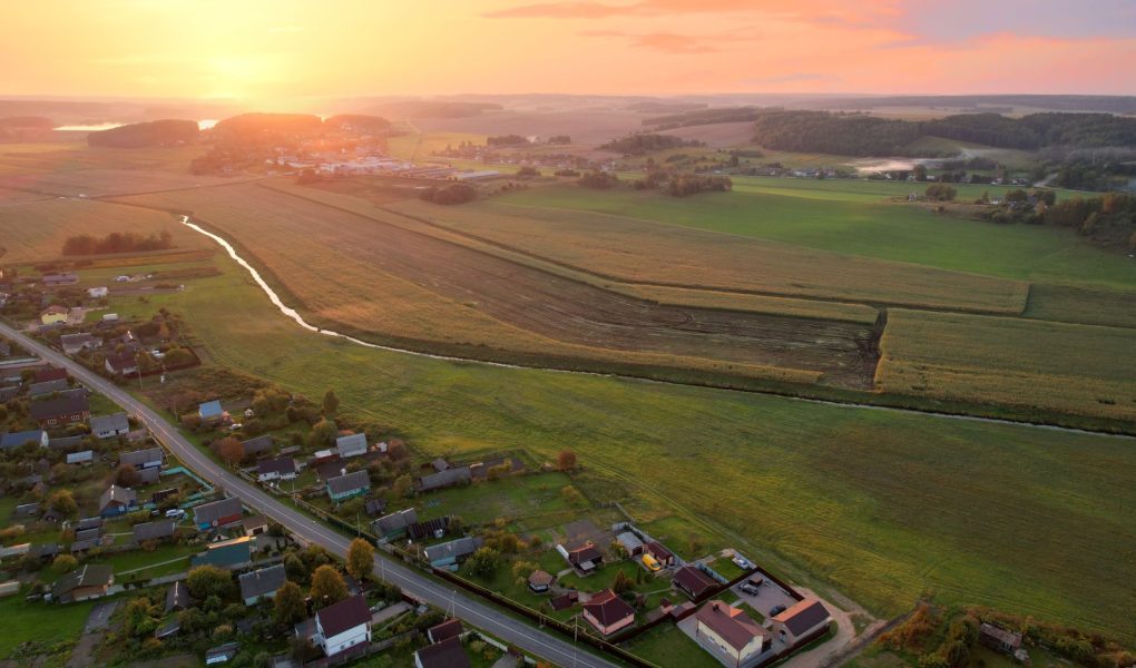 Wiejskie domy na wsi. Widok z lotu ptaka na dachy zielonego pola z wiejskimi domami. Wieś z drewnianym domem. Podmiejski dom na farmie. Mieszkania poza miastem. Rolnictwo, rolnictwo i agronomia.