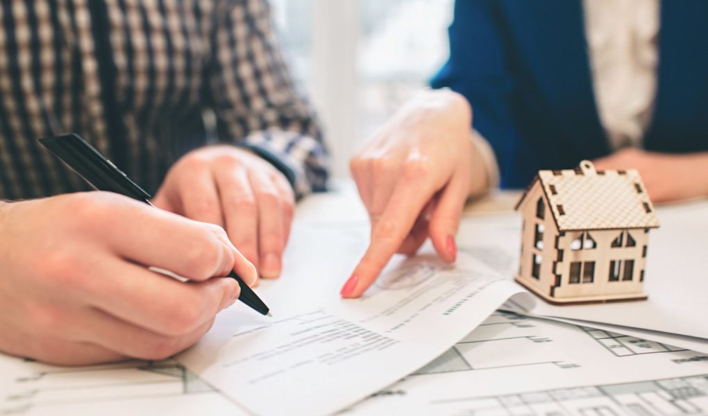 Młoda para rodzinna kupuje nieruchomość na wynajem. Agent udzielający konsultacji mężczyźnie i kobiecie. Podpisanie umowy na zakup domu lub mieszkania. Podpisanie umowy lub porozumienia. Dokumentacja biznesowa.