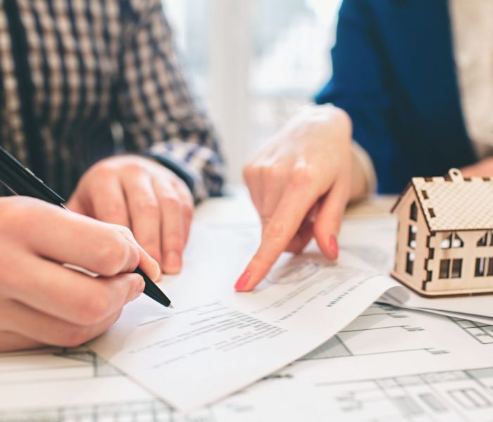 Młoda para rodzinna kupuje nieruchomość na wynajem. Agent udzielający konsultacji mężczyźnie i kobiecie. Podpisanie umowy na zakup domu lub mieszkania. Podpisanie umowy lub porozumienia. Dokumentacja biznesowa.