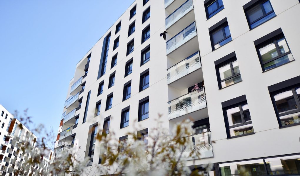 Krajobraz dzielnicy mieszkalnej z nowoczesnymi budynkami mieszkalnymi, nowy krajobraz miejski w mieście. Budynek mieszkalny z białymi fasadami. Nowoczesna minimalistyczna architektura z dużą ilością kwadratowych szklanych okien.