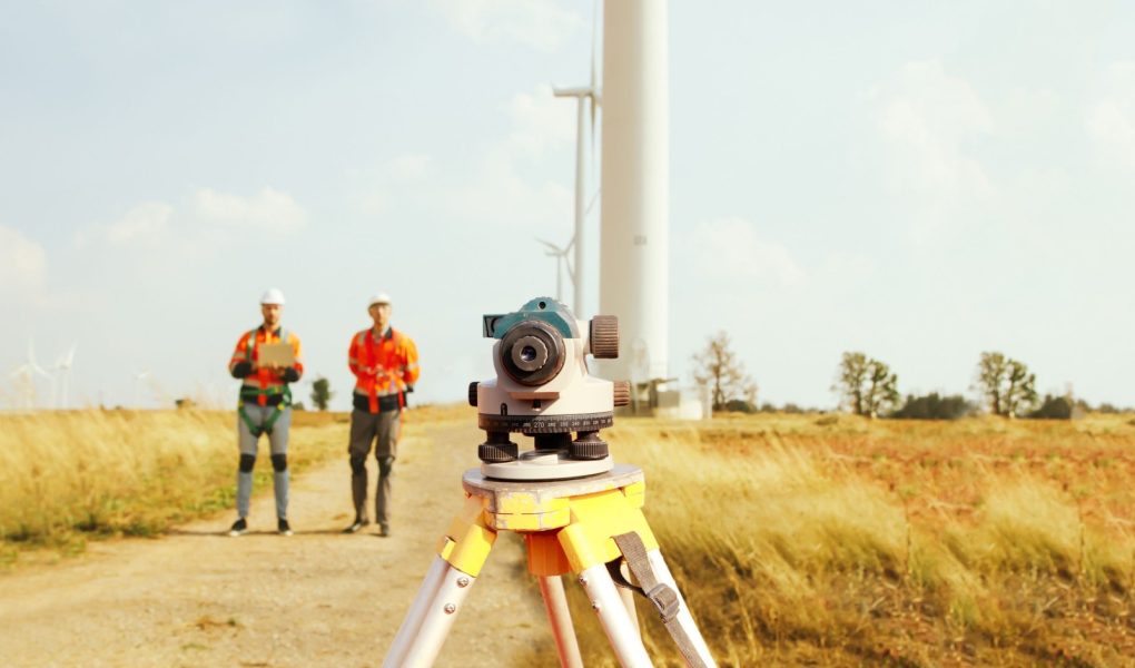 Zespół architektów i geodetów pracujący z teleskopem geodezyjnym do pomiaru wysokości obszarów spacerowych, pomiarów pól wiatrowych, planowania budowy dróg przy użyciu profesjonalnych narzędzi.