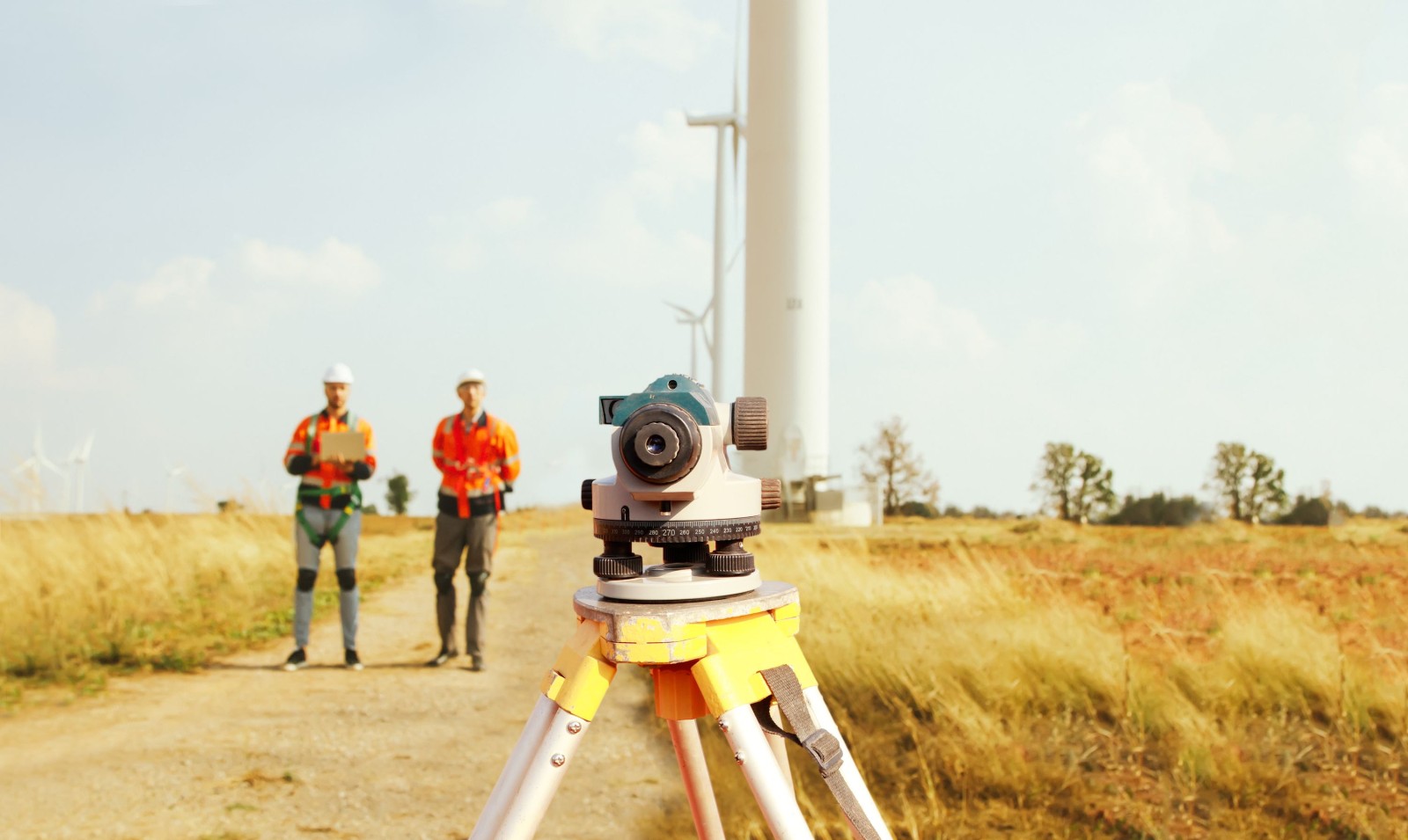 Zespół architektów i geodetów pracujący z teleskopem geodezyjnym do pomiaru wysokości obszarów spacerowych, pomiarów pól wiatrowych, planowania budowy dróg przy użyciu profesjonalnych narzędzi.