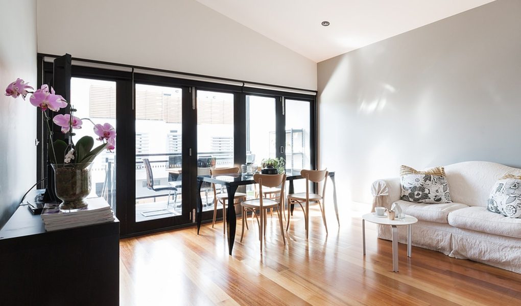 Duży salon w apartamencie typu studio ze składanymi drzwiami balkonowymi