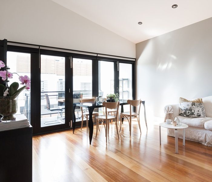 Duży salon w apartamencie typu studio ze składanymi drzwiami balkonowymi