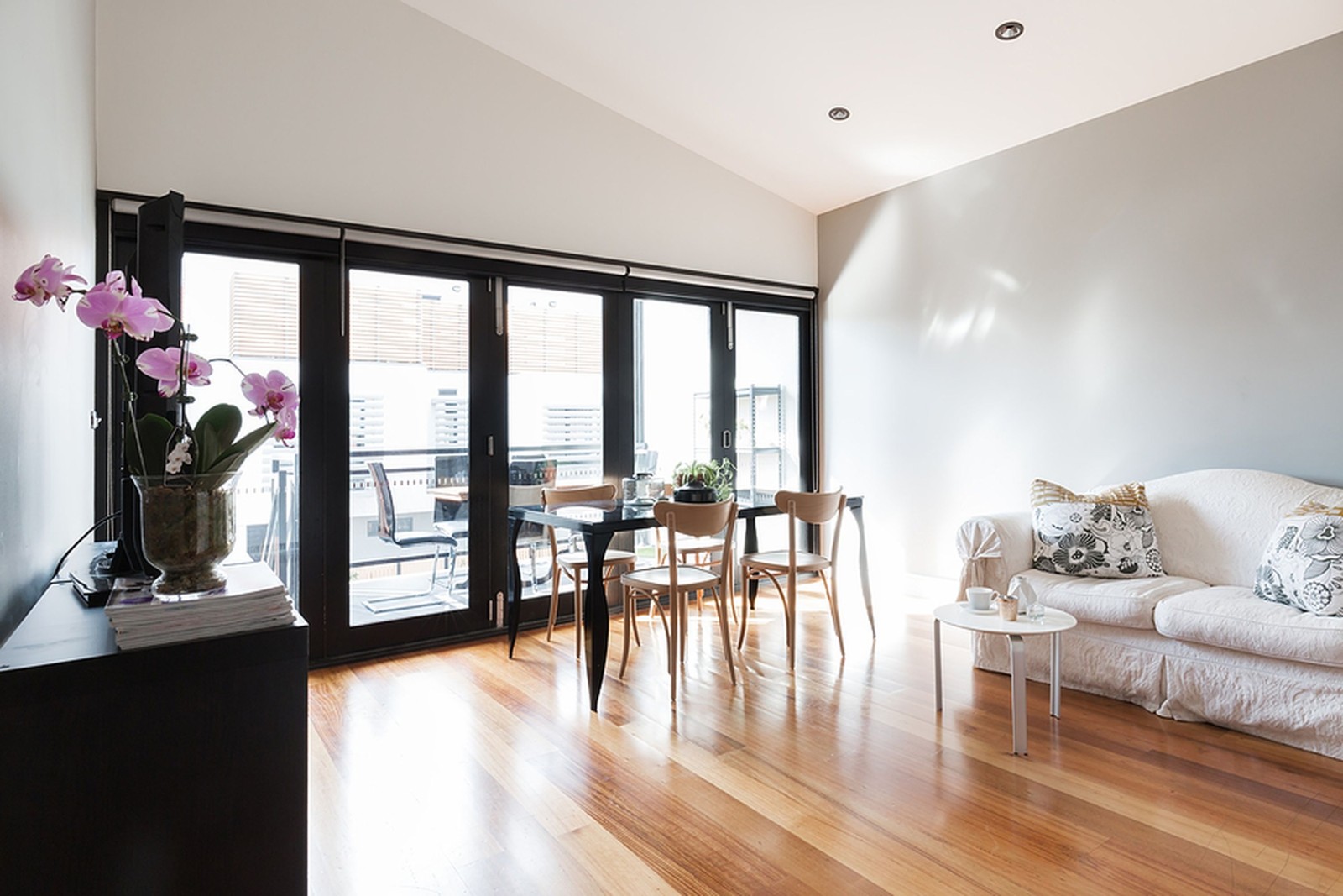 Duży salon w apartamencie typu studio ze składanymi drzwiami balkonowymi
