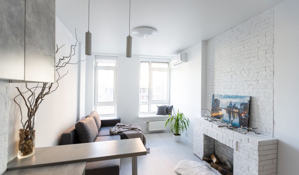 Wnętrze małego salonu z wyposażoną kuchnią w apartamentach typu studio w minimalistycznym stylu z jasnym kolorem
