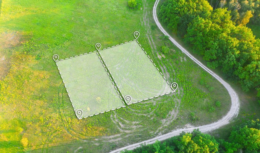 Działka pod zabudowę mieszkaniową na zielonym polu - ujęcie z drona. Oznaczenie topograficzne dwóch działek pod budowę prywatnej rezydencji. Oznaczenie planu działki z białą nakładką.