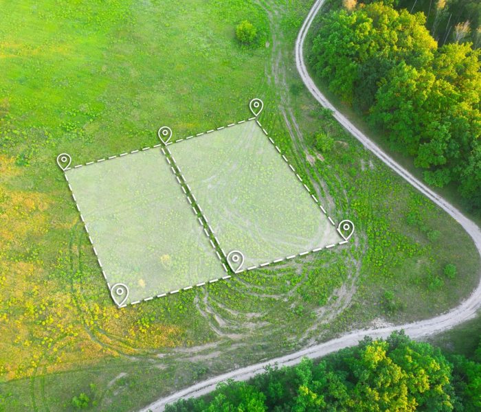 Działka pod zabudowę mieszkaniową na zielonym polu - ujęcie z drona. Oznaczenie topograficzne dwóch działek pod budowę prywatnej rezydencji. Oznaczenie planu działki z białą nakładką.