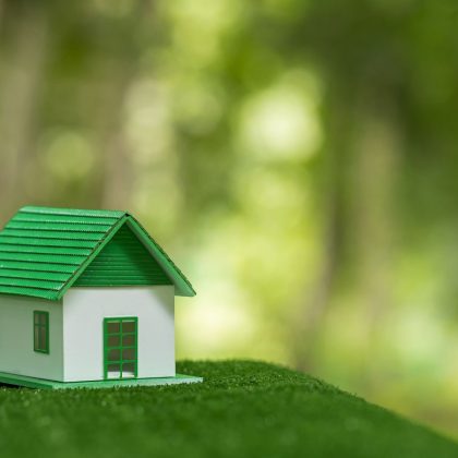 Przyjazny dla środowiska dom nieruchomości. Mały model domu nieruchomości na trawie w zielonej ekologii przyrody. Zrównoważony projekt mieszkaniowy oszczędzający energię i sprzedaż - wynajem koncepcji biznesowej