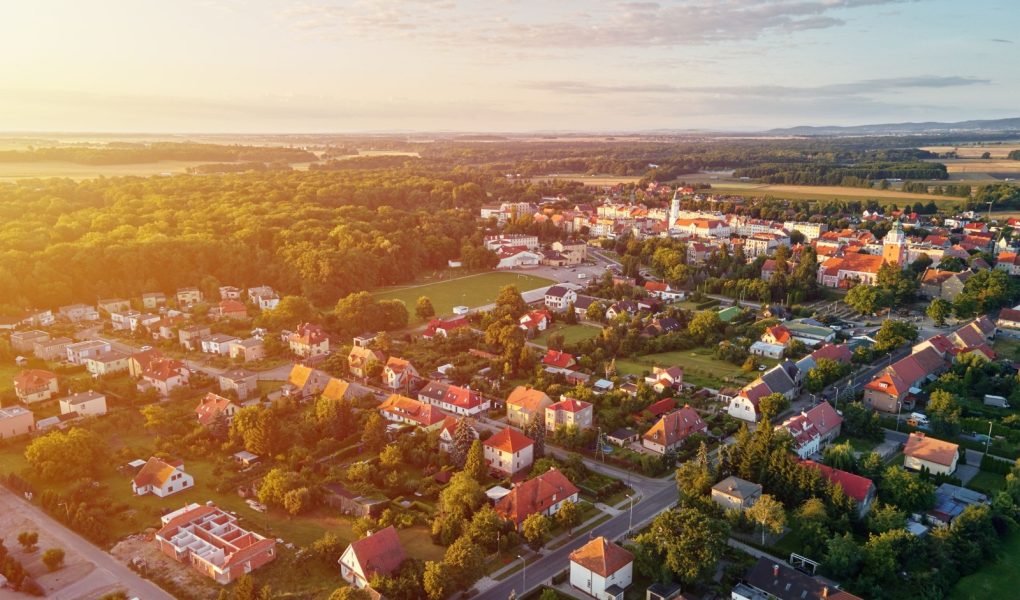 Widok z lotu ptaka na podmiejską dzielnicę, dzielnicę mieszkaniową z budynkami i ulicami w małym europejskim miasteczku o zachodzie słońca