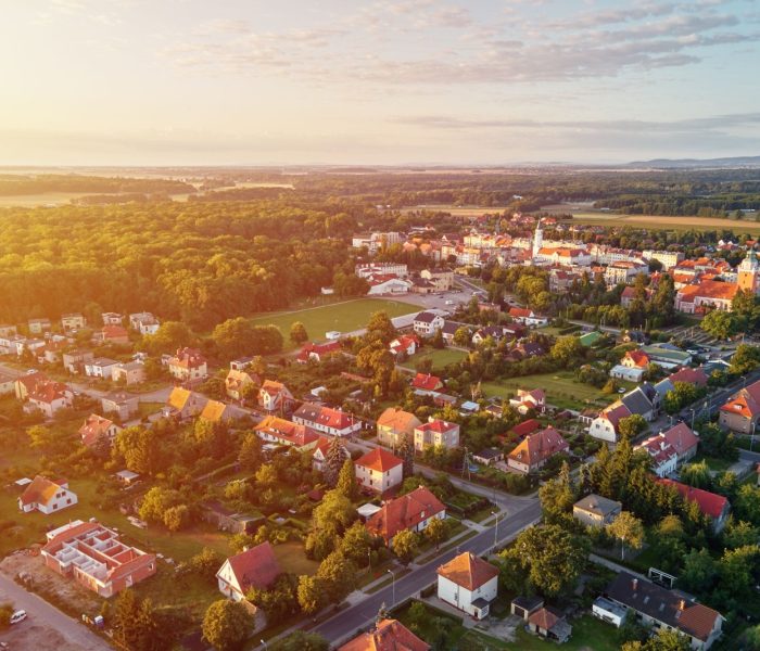 Widok z lotu ptaka na podmiejską dzielnicę, dzielnicę mieszkaniową z budynkami i ulicami w małym europejskim miasteczku o zachodzie słońca
