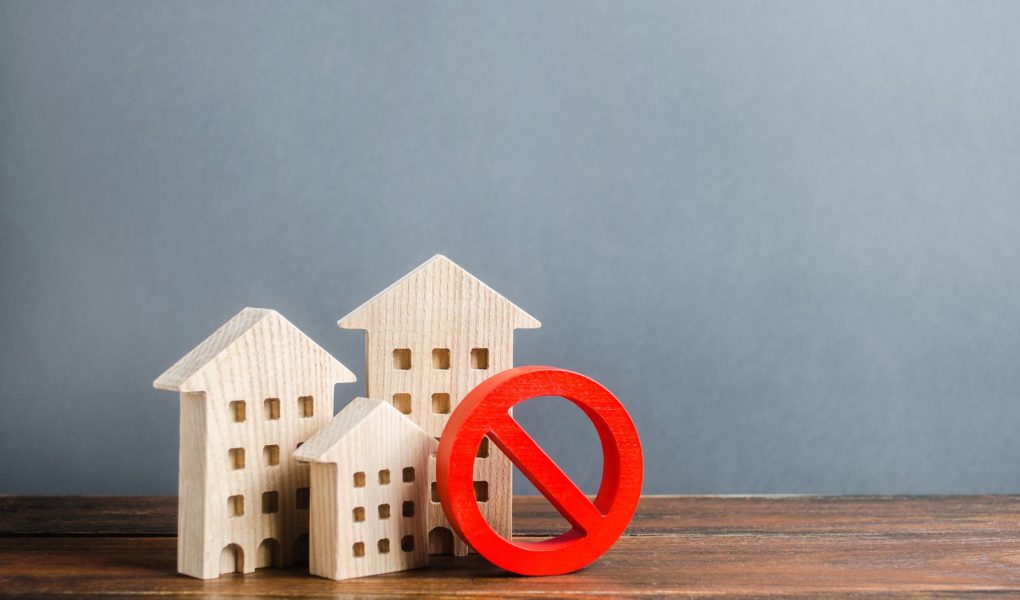 Budynki mieszkalne i czerwony symbol zakazu NIE. Niedostępne i drogie mieszkania. Brak przestrzeni życiowej i niemożność zbudowania nowej. Ograniczenia i zakazy dotyczące pięter.