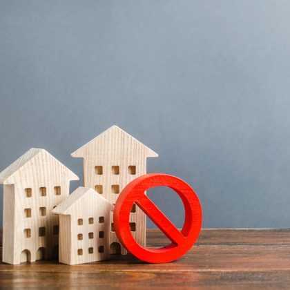 Budynki mieszkalne i czerwony symbol zakazu NIE. Niedostępne i drogie mieszkania. Brak przestrzeni życiowej i niemożność zbudowania nowej. Ograniczenia i zakazy dotyczące pięter.