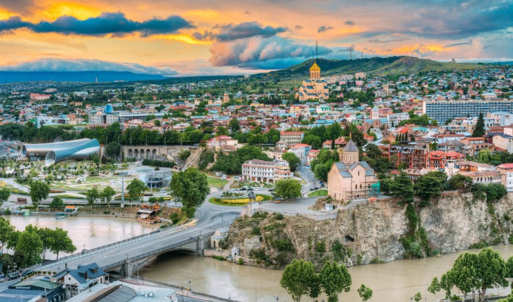 Wieczorny widok na Tbilisi o kolorowym zachodzie słońca, Gruzja. Letni krajobraz miasta. Na zdjęciu widoczna nowa sala koncertowa, rezydencja Avlabar - administracja prezydencka Gruzji, katedra Świętej Trójcy w Tbilisi, kościół Metekhi