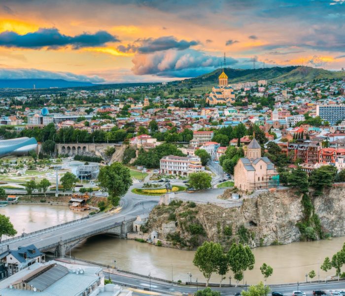 Wieczorny widok na Tbilisi o kolorowym zachodzie słońca, Gruzja. Letni krajobraz miasta. Na zdjęciu widoczna nowa sala koncertowa, rezydencja Avlabar - administracja prezydencka Gruzji, katedra Świętej Trójcy w Tbilisi, kościół Metekhi