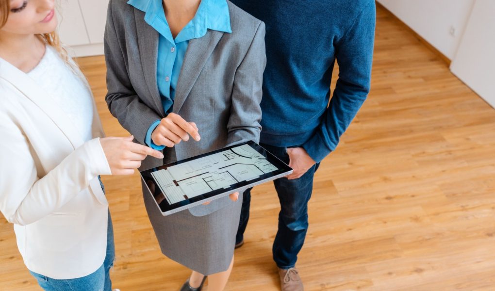 Broker zakwaterowania pokazujący plan mieszkania klientom chcącym je kupić lub wynająć