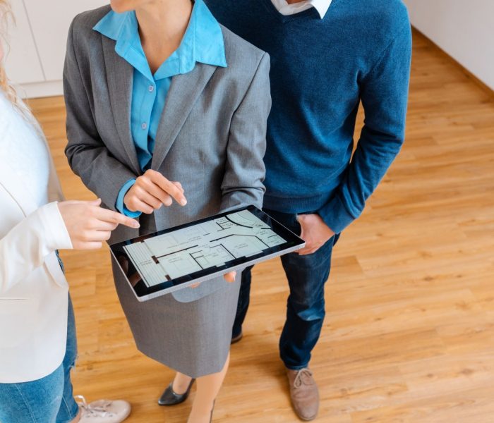 Broker zakwaterowania pokazujący plan mieszkania klientom chcącym je kupić lub wynająć