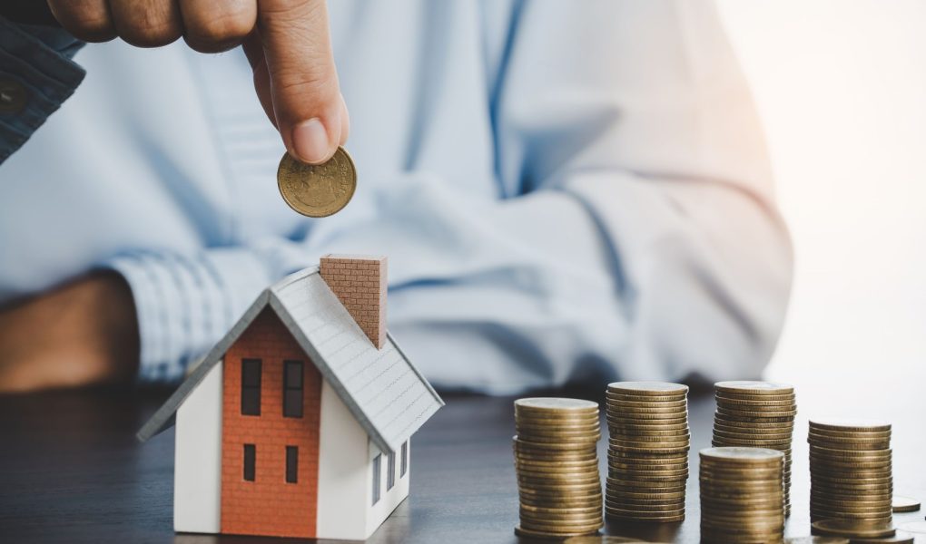 Ręka wkładająca monetę do domu model monety do oszczędzania pieniędzy na zakup domu. Plany oszczędnościowe dla domu, pożyczki, inwestycji, kredytu hipotecznego, finansów i bankowości o koncepcji domu.