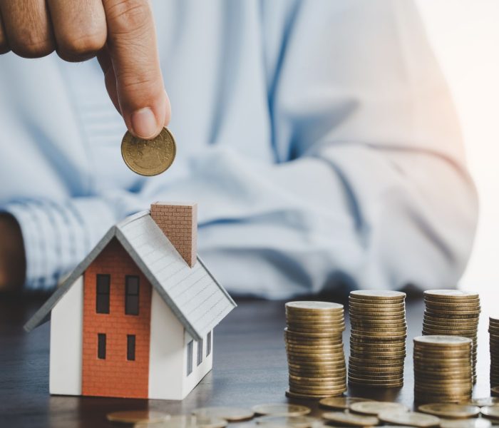 Ręka wkładająca monetę do domu model monety do oszczędzania pieniędzy na zakup domu. Plany oszczędnościowe dla domu, pożyczki, inwestycji, kredytu hipotecznego, finansów i bankowości o koncepcji domu.