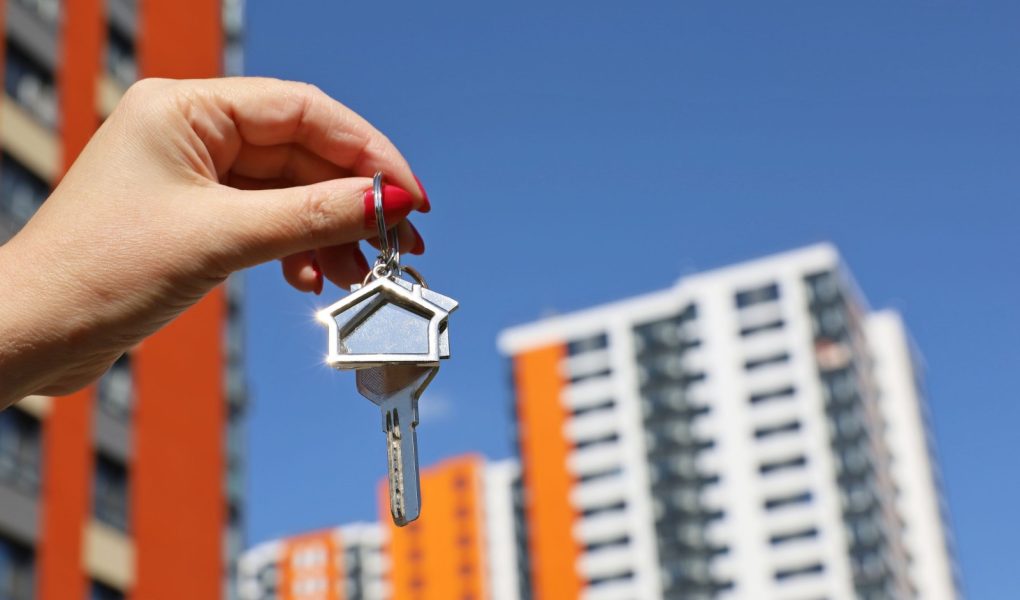 Agent nieruchomości, klucze do domu w kobiecej dłoni na tle nowego budynku. Byung mieszkanie lub wynajem nieruchomości