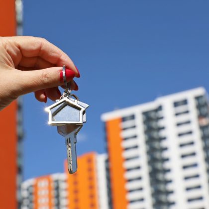 Agent nieruchomości, klucze do domu w kobiecej dłoni na tle nowego budynku. Byung mieszkanie lub wynajem nieruchomości