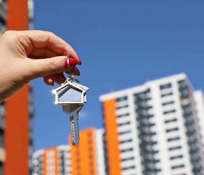 Agent nieruchomości, klucze do domu w kobiecej dłoni na tle nowego budynku. Byung mieszkanie lub wynajem nieruchomości