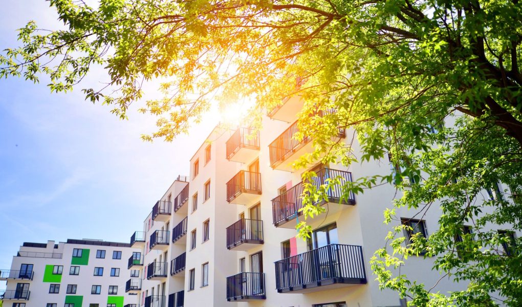 Ekologiczna architektura mieszkaniowa. Nowoczesny budynek mieszkalny w otoczeniu drzew. Ekologia i zielone życie w mieście, koncepcja środowiska miejskiego. Nowoczesny budynek mieszkalny i zielone drzewa.