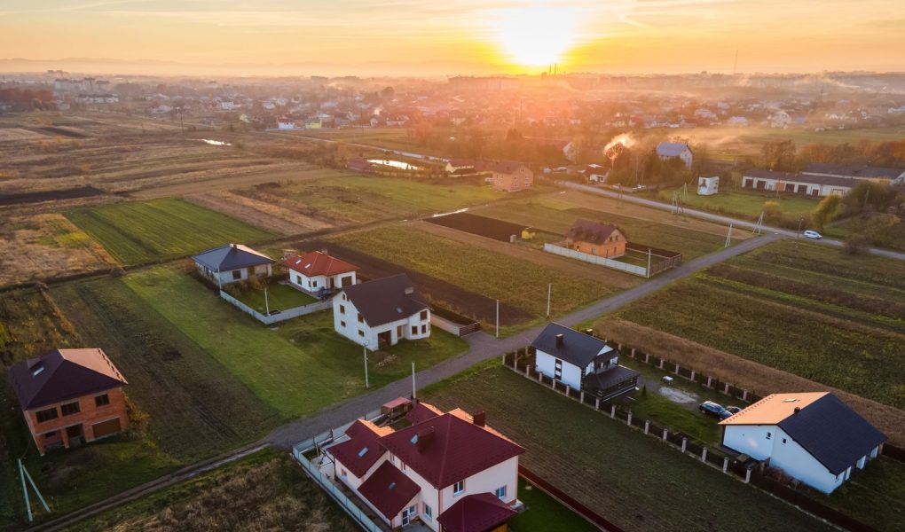 Widok z lotu ptaka na prywatne domy w wiejskiej strefie podmiejskiej o zachodzie słońca.
