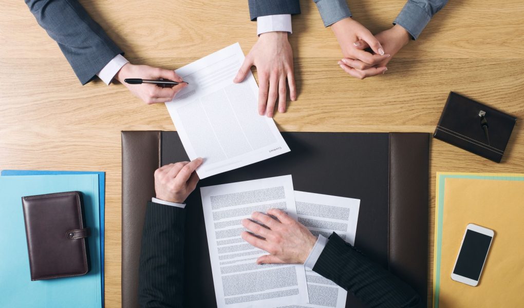 Biznesmen i kobieta siedzący przy biurku prawnika i podpisujący ważne dokumenty ręce widok z góry nierozpoznawalni ludzie