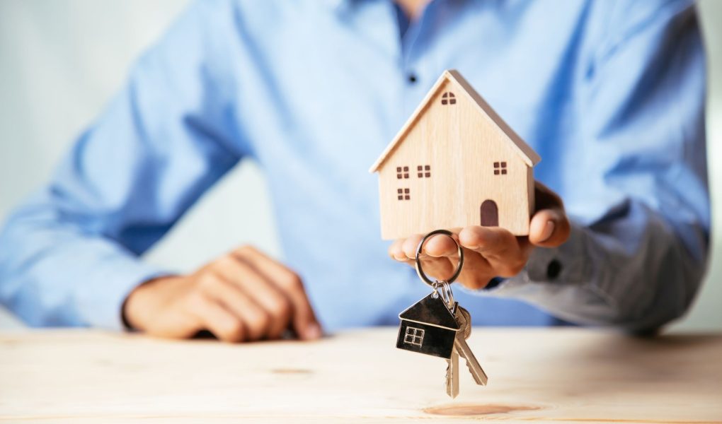 Model domu z agentem nieruchomości i klientem omawiającym umowę kupna domu, ubezpieczenia lub kredytu na nieruchomości, koncepcja nieruchomości.