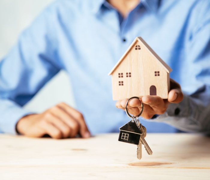 Model domu z agentem nieruchomości i klientem omawiającym umowę kupna domu, ubezpieczenia lub kredytu na nieruchomości, koncepcja nieruchomości.