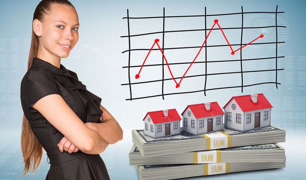 Bizneswoman uśmiecha się i stoi ze skrzyżowanymi ramionami. Pakiety dolarów z domami szeregowymi jako tło