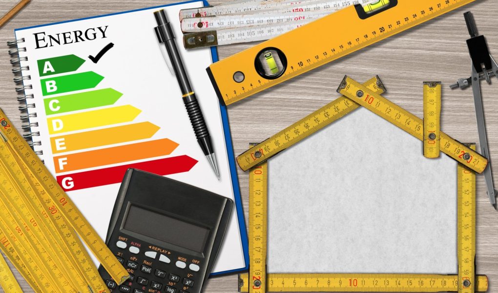 Linijka na biurku w kształcie ekologicznego domu z oceną efektywności energetycznej i kalkulatorem. Projekt domu ekologicznego