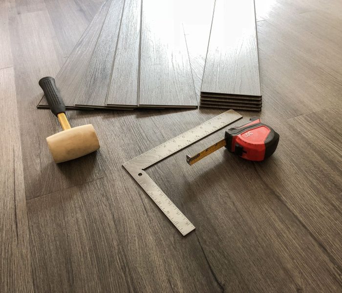 Koncepcja luksusowej podłogi. Podłoga laminowana z desek winylowych. Pracownik przygotowujący się do montażu nowej podłogi. Narzędzia na podłodze. Podłoga z twardego drewna. Podłoga z płytek. Podłoga winylowa. Nowoczesne płytki podłogowe.