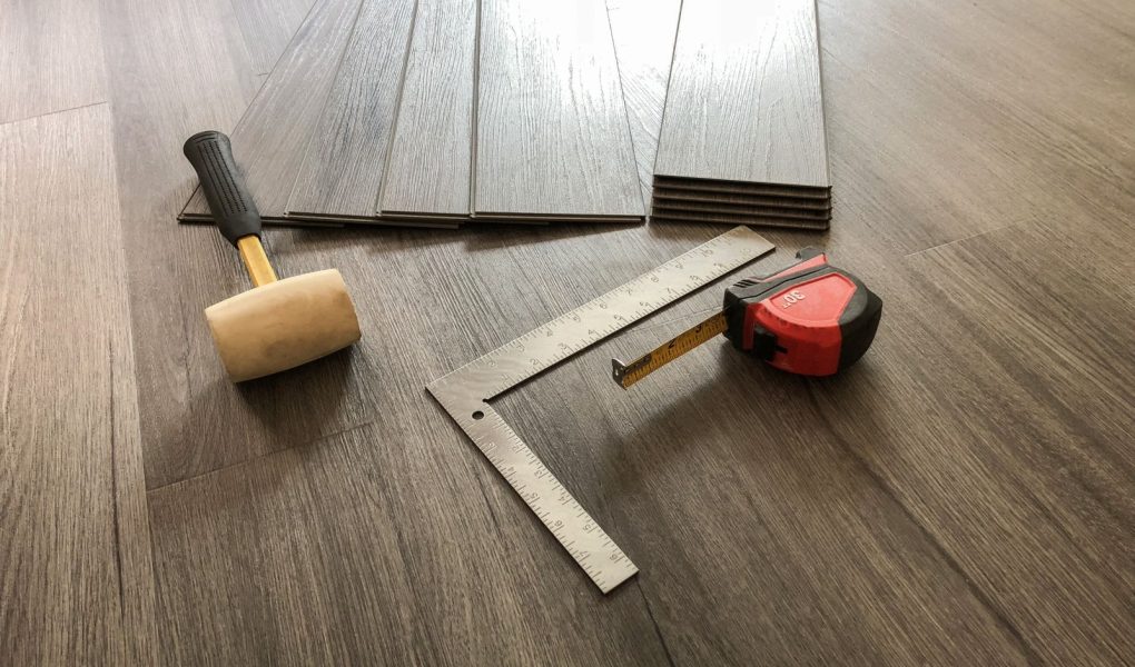 Koncepcja luksusowej podłogi. Podłoga laminowana z desek winylowych. Pracownik przygotowujący się do montażu nowej podłogi. Narzędzia na podłodze. Podłoga z twardego drewna. Podłoga z płytek. Podłoga winylowa. Nowoczesne płytki podłogowe.