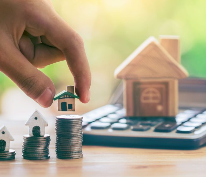 Dom na monetach i dom umieścić na kalkulatorze. Ręka człowieka kładzie dom. planowanie oszczędności monet na zakup domu koncepcja drabiny nieruchomości, kredytów hipotecznych i inwestycji w nieruchomości. oszczędzanie na dom.
