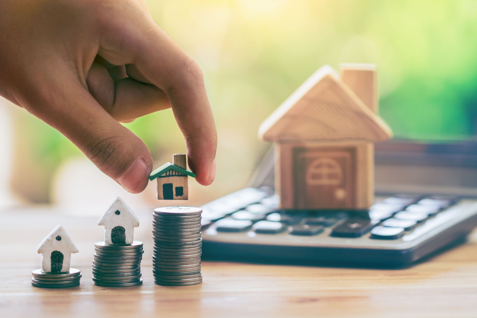 Dom na monetach i dom umieścić na kalkulatorze. Ręka człowieka kładzie dom. planowanie oszczędności monet na zakup domu koncepcja drabiny nieruchomości, kredytów hipotecznych i inwestycji w nieruchomości. oszczędzanie na dom.