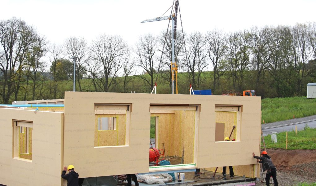 Montaż prefabrykowanego domu drewnianego z dźwigiem w tle