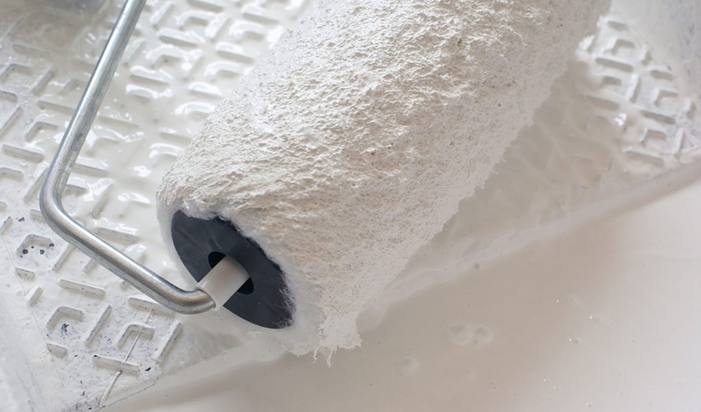 Wałek malarski w białej farbie gotowy do użycia.