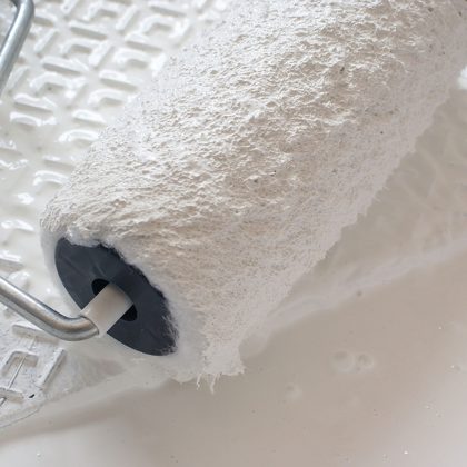 Wałek malarski w białej farbie gotowy do użycia.