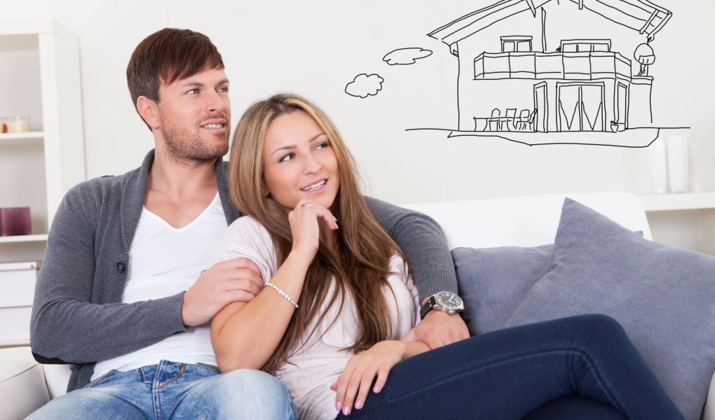 Młoda zamyślona para siedząca na sofie i myśląca o zakupie własnego domu