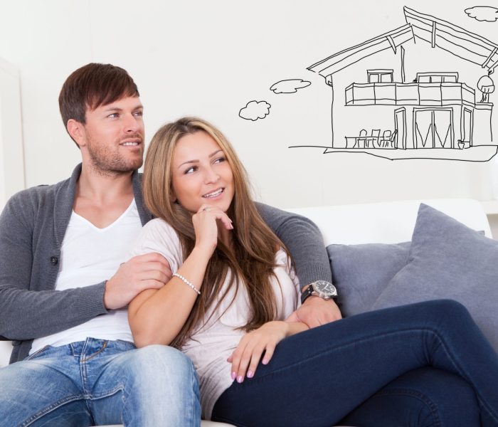 Młoda zamyślona para siedząca na sofie i myśląca o zakupie własnego domu