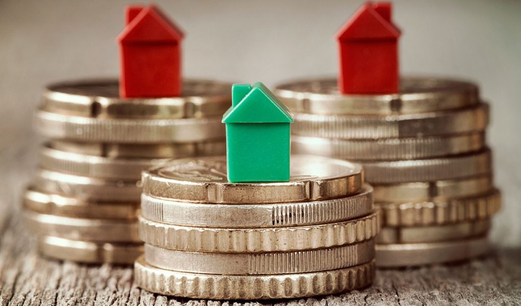 Miniaturowe domy spoczywające na stosach monet. Koncepcja hipotecznej drabiny nieruchomości i inwestycji w nieruchomości