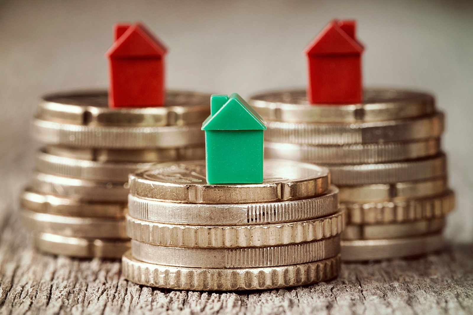 Miniaturowe domy spoczywające na stosach monet. Koncepcja hipotecznej drabiny nieruchomości i inwestycji w nieruchomości