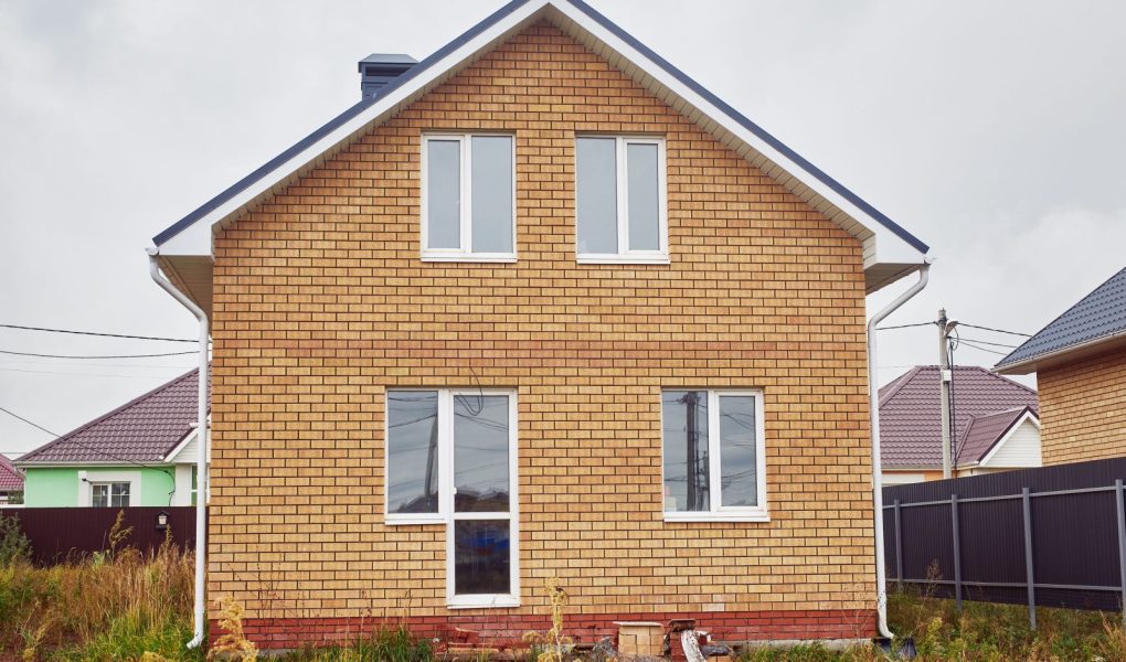 Nowy dwupiętrowy dom z cegły z dwuspadowym dachem.